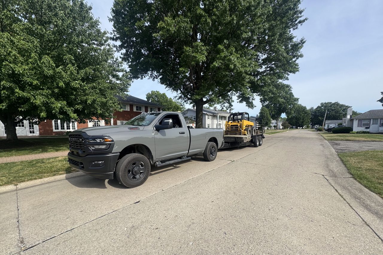 The Grade A pickup towing the compact loader to a job